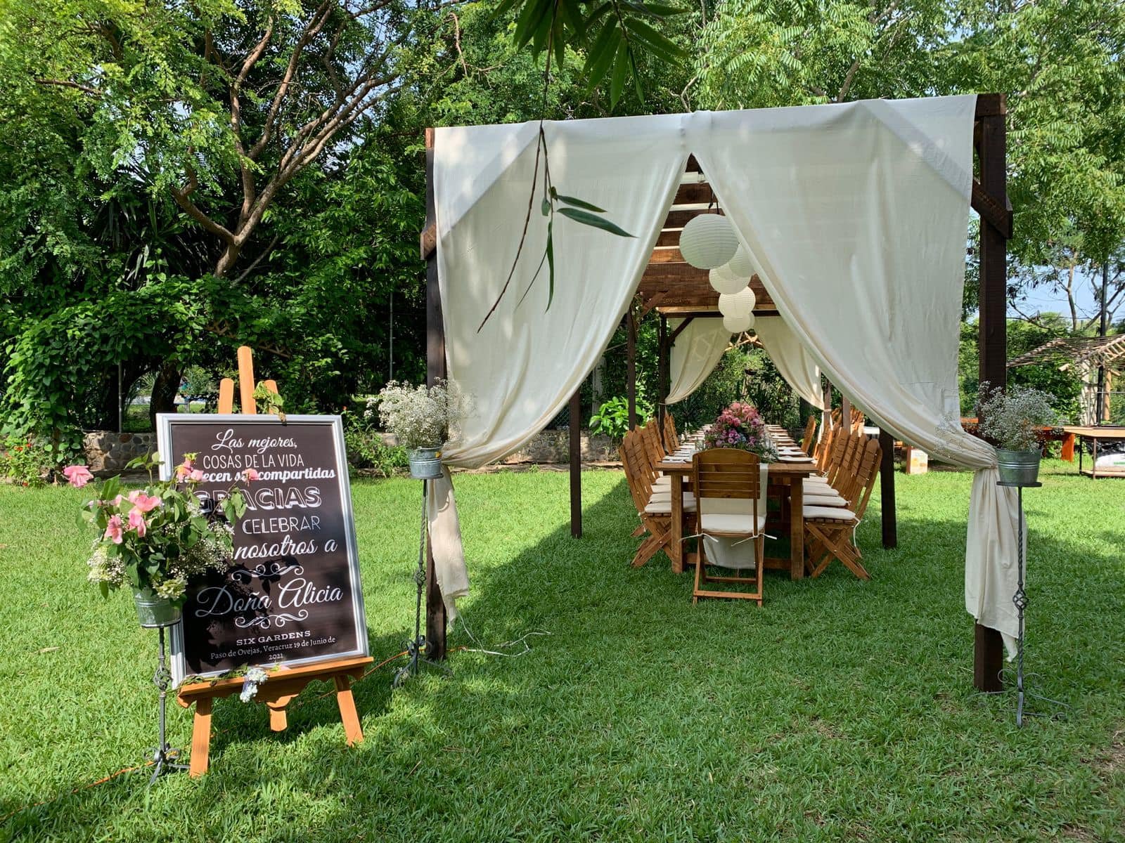 Pérgola con cortinas blancas y letrero de bienvenida